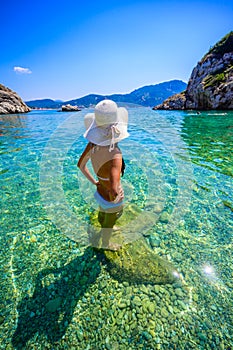 Girl with sun hat relaxing and swimming at Porto Timoni beach at Afionas is a paradise double beach with crystal clear azure water