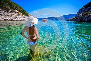 Girl with sun hat relaxing and swimming at Porto Timoni beach at Afionas is a paradise double beach with crystal clear azure water