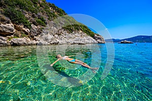 Girl with sun hat relaxing and swimming at Porto Timoni beach at Afionas is a paradise double beach with crystal clear azure water