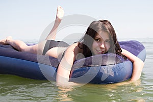 Girl sunbathing on air mattress in sea