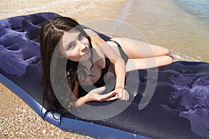 Girl sunbathing on air mattress in sea