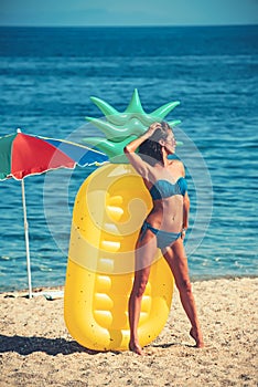 Girl sunbathing on beach with air mattress. girl in swimsuit on sunny beach.