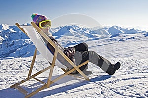 Girl sunbathing in a deckchair on the side of a ski slope