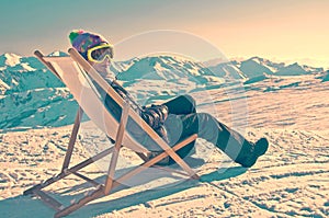 Girl sunbathing in a deckchair on the side of a ski slope, vintage