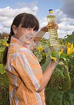 The girl with sunflower and bottle of oil