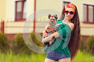 Girl in sunglasses with dog yorkie on hands