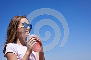 Girl in sunglasses drinking cold lemonade
