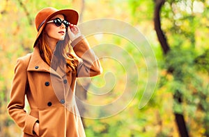 Girl in sunglasses and hat in the autumn park.