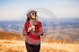 Girl in sunglasses with hat walk with happiness on top of mountain range in autumn