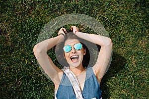 Girl with sunglasses lying on the grass in summer day in city park