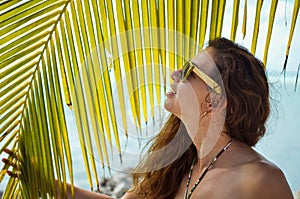 Girl with sunglasses posing next to a palm tree