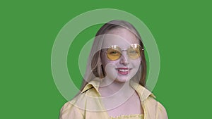 Girl in sunglasses smiling at camera on green background