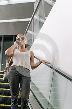 Girl with sunglasses talking on her mobile phone in an escalator