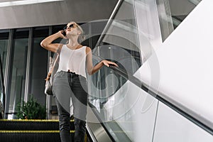 Girl with sunglasses talking on her mobile phone in an escalator