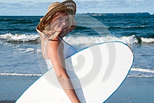 Girl in sunhat with surfboard photo