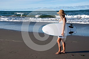 Girl in sunhat with surfboard