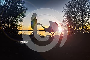 A girl at sunset walks with a baby in a stroller on an autumn day.