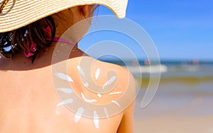 Girl with suntan lotion at the beach in form of the sun