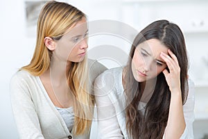 Girl supporting depressed female friend indoors