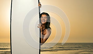 Girl with surf board ready to surfing. Woman surfer holding surfboard on a beach at sunset or sunrise. Surfing at