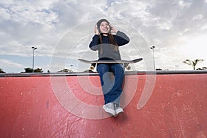 girl with surf skate smilling and listening music