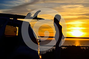 Girl and surfboard silhouettes at sunset