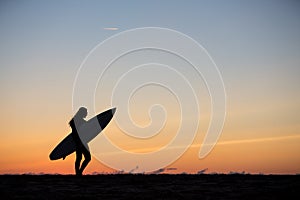 girl with surfboard in sunset at beach