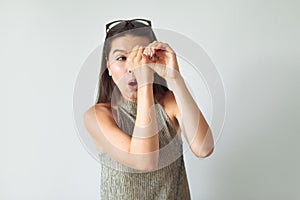 Girl with surprise peeps through binoculars made of hands. discovery of secrets