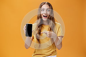 Girl surprised with awesome smartphone features. Portrait of delighted and amazed cute european slender woman with wavy