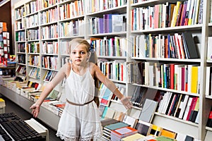 Girl surprised chooses a book in the library