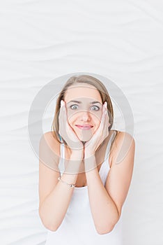 A girl with surprised expression while touching her face with her hands.