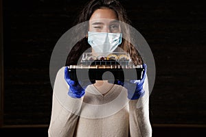Girl with sushi. Food courier in medical mask. Delivery at quarantine coronavirus covid-19. Young woman holding 2 sushi