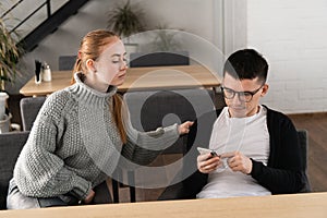 Girl suspects her man in cheating on her and spying sitting near in the cafe. Mistrust concept