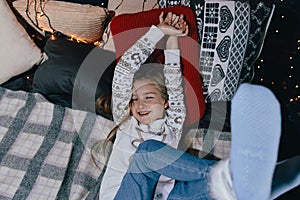 Girl in a sweater on the bed on a winter day. Girl having fun in home