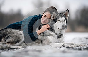 Girl in sweater lies and hugs dog Alaskan Malamute photo
