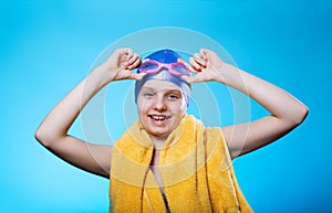 Girl swimmer in a bathing cap and glasses. The girl holds glasses for diving. She laughs. The concept of success.