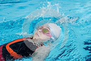 Girl swimming backstroke in pool