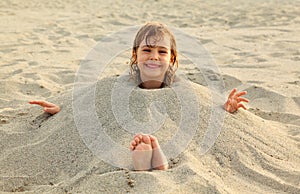 Girl after swimming is buried in sand on beach