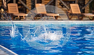 A girl with swimming goggles jumps into a pool with clear water on the background of a warm summer sunny sunset