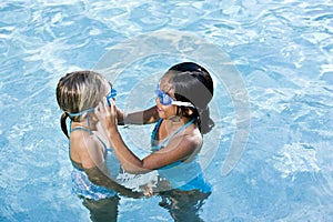 Girl in swimming pool help friend with goggles