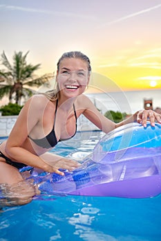 The girl is swimming in the pool on an inflatable mattress