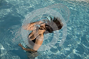 Girl in a swimming pool throwing wet hair