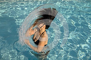 Girl in a swimming pool throwing wet hair