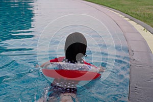 The girl is swimming with a red lifebuoy ring in one of the hotel`s pools