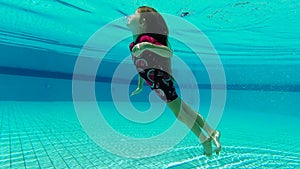 Girl is swimming under water in the pool. Slow motion video