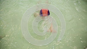 A girl swims in a pool underwater. A girl in a swimsuit learns to swim underwater in the pool.