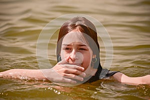 A girl swims in the river. Close up of young beautiful girl in water