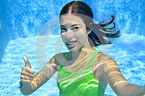 Girl swims in swimming pool underwater, happy active teenager dives and has fun under water, kid fitness on family vacation