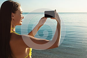 Girl In Swimsuit Holding Phone Taking Picture Of Sea Outdoors