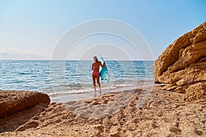 Girl in swimsuit ready to surf in sea. Hot day on beach and ocean view. Idea of summer, relax and desire of adventure